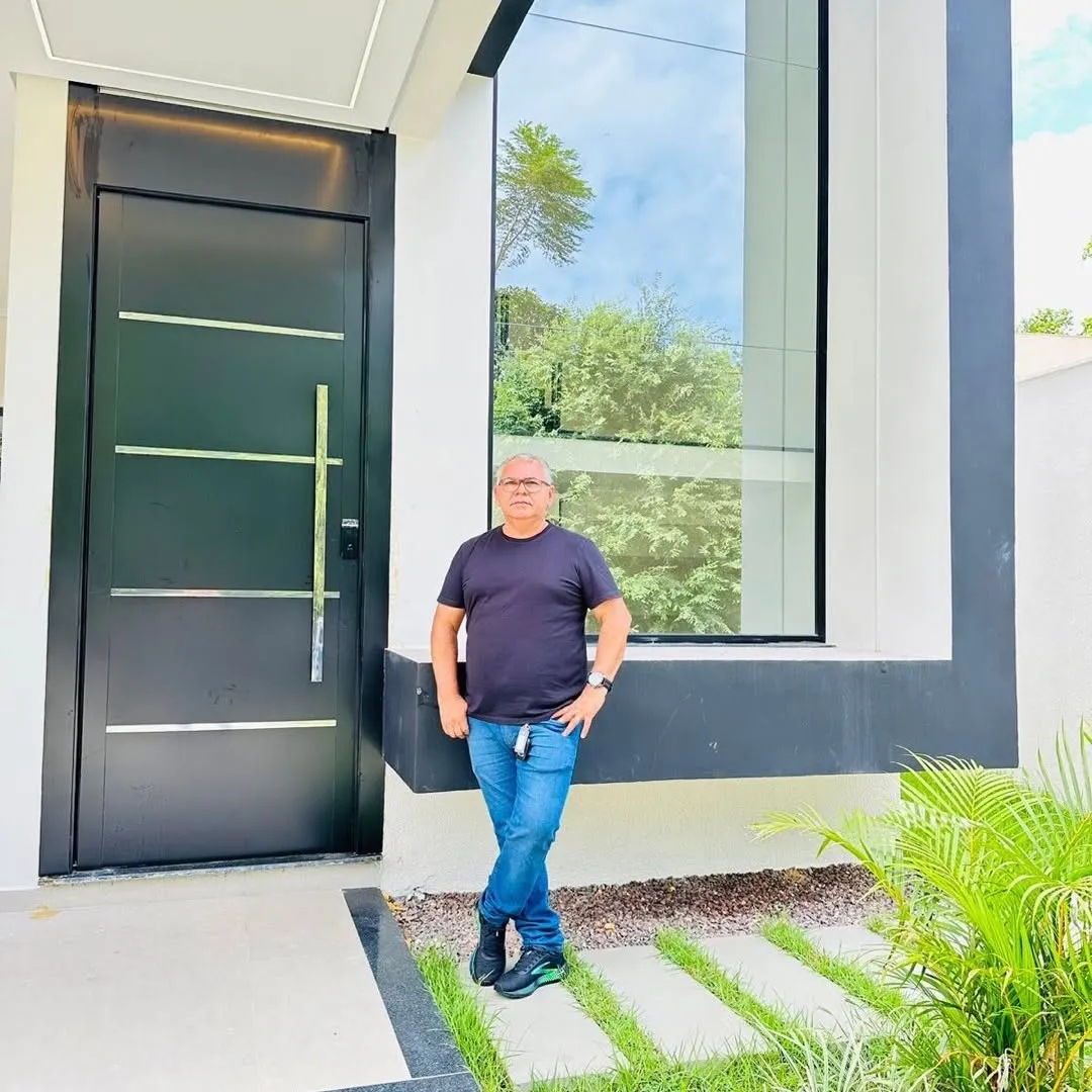 Fachada moderna de casa entregue, porta pivotante preta e vidro