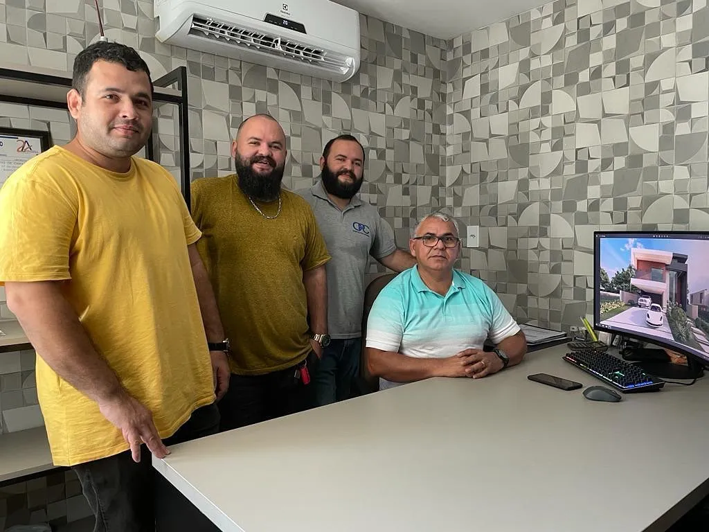 Equipe da Construtora Opcional no escritório com projeto na tela
