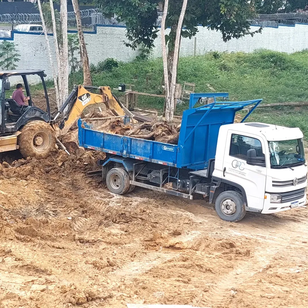 Caminhão da Construtora Opcional e retroescavadeira em terraplanagem