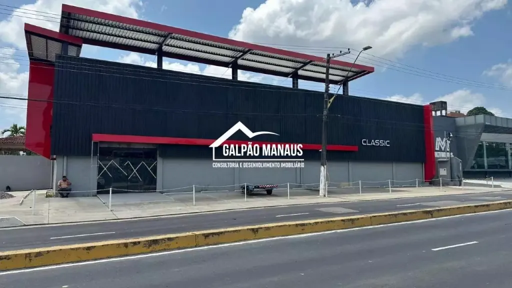 Fachada de galpão comercial com revestimento metálico escuro, detalhes em vermelho e vitrine de show-room