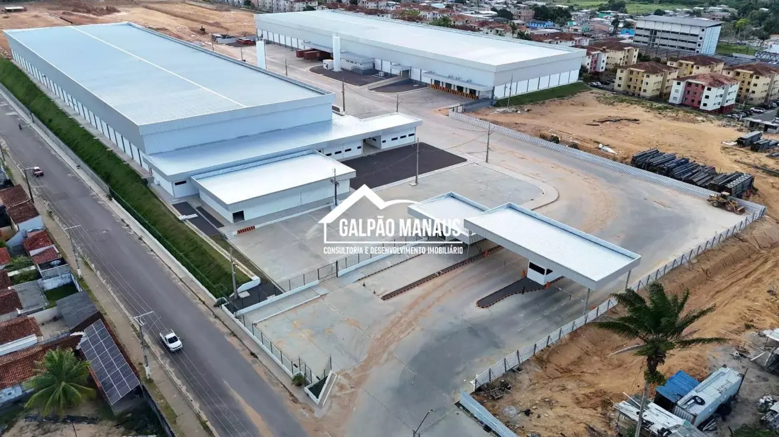 Vista aérea do complexo de galpões, com pátio de manobra pavimentado, guarita de acesso coberta e terreno cercado no Distrito Industrial de Manaus