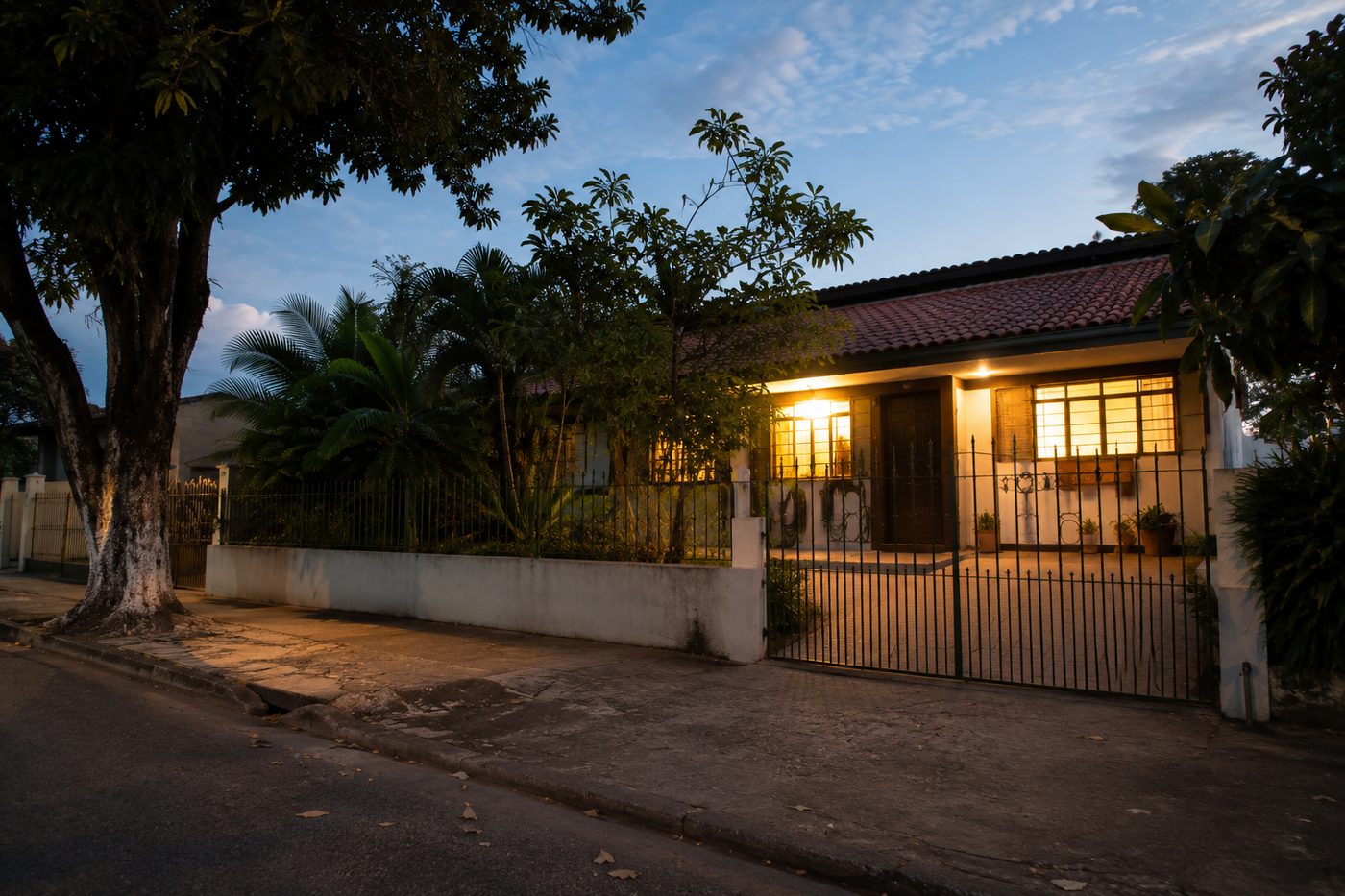 Casa térrea de bairro com as luzes acesas no início da noite