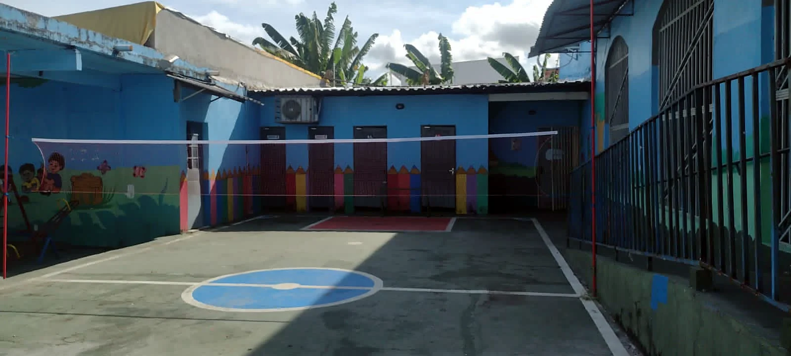 Quadra da escola com rede de vôlei e mural pintado
